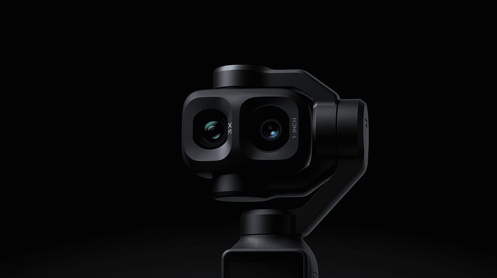 Dual-lens camera mounted on a black handheld gimbal against a dark background, showcasing stabilization hardware.