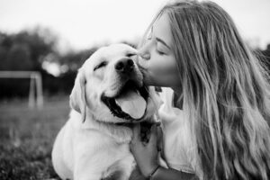 Girl kissing her dog outside backyard black and white photo