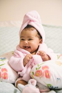 Baby in a spa robe and hair towel laughing