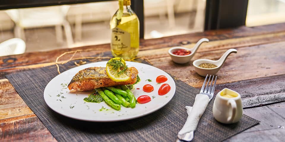 Wooden table with plate of salmon and sides