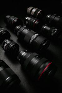 Several camera lenses of varying sizes arranged on a dark surface.