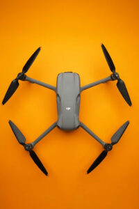 Top-down view of a gray DJI quadcopter drone with four propellers on an orange background
