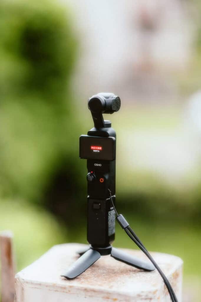 DJIPocket | Photography and video news, reviews and tips | Henry's Camera Osmo handheld gimbal on a small tripod outdoors with a blurred green background