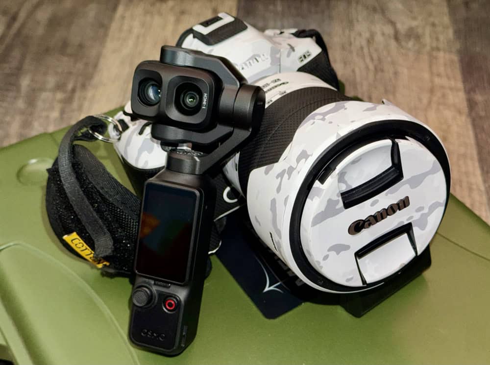 Canon camera with a camouflage-pattern lens mounted on a handheld stabilizer with a small LCD screen attachment