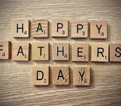 Wooden Scrabble tiles spell 'HAPPY FATHER'S DAY' on a light wood surface for a celebration message.