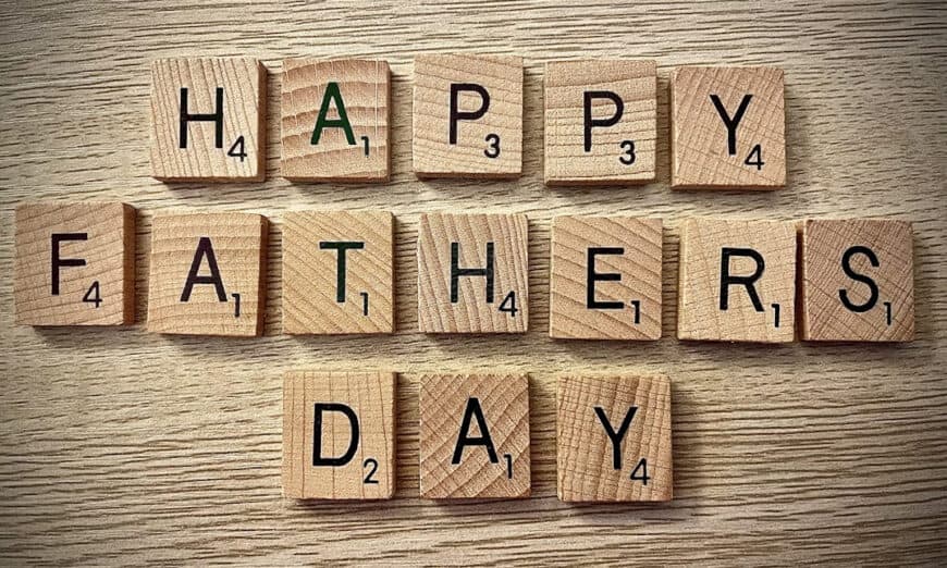 Wooden Scrabble tiles spell 'HAPPY FATHER'S DAY' on a light wood surface for a celebration message.