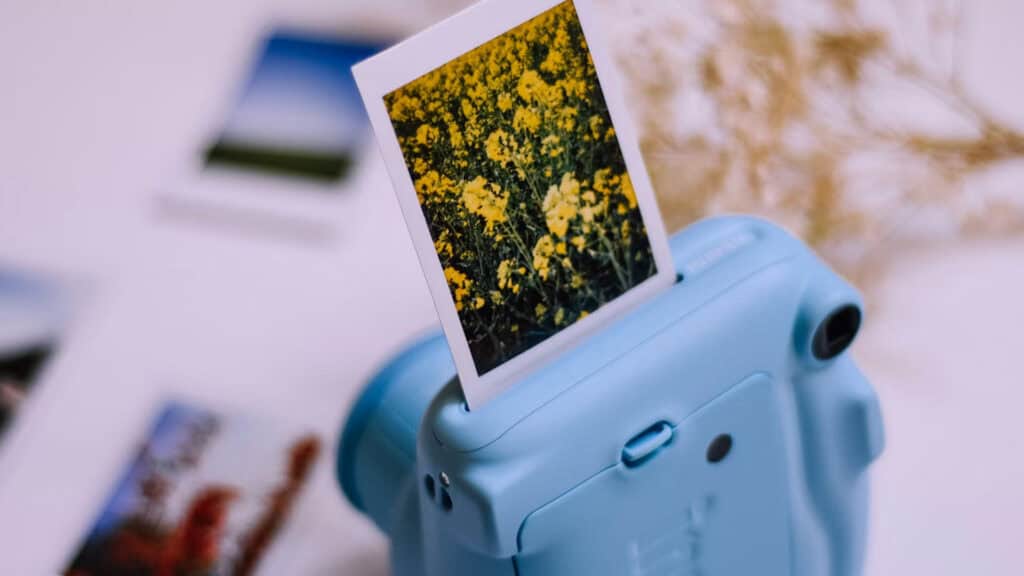 Instant2 | Photography and video news, reviews and tips | Henry's Camera Blue handheld photo printer with a printed image of yellow flowers visible in the foreground