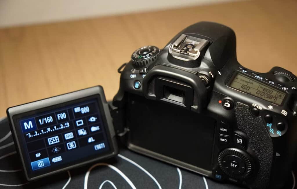 Manual | Photography and video news, reviews and tips | Henry's Camera DSLR camera with its flip-out LCD showing manual exposure settings (shutter speed 1/160, ISO 800) on a desk surface.