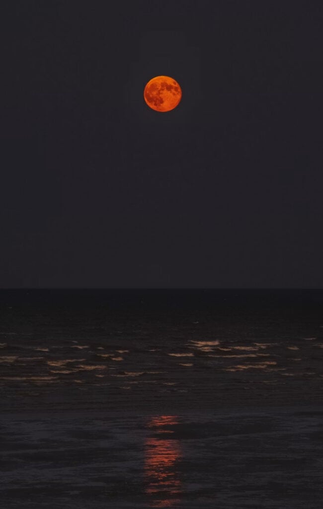 Moon | Photography and video news, reviews and tips | Henry's Camera Bright orange full moon over dark sea with its red reflection shimmering on gentle waves at night.