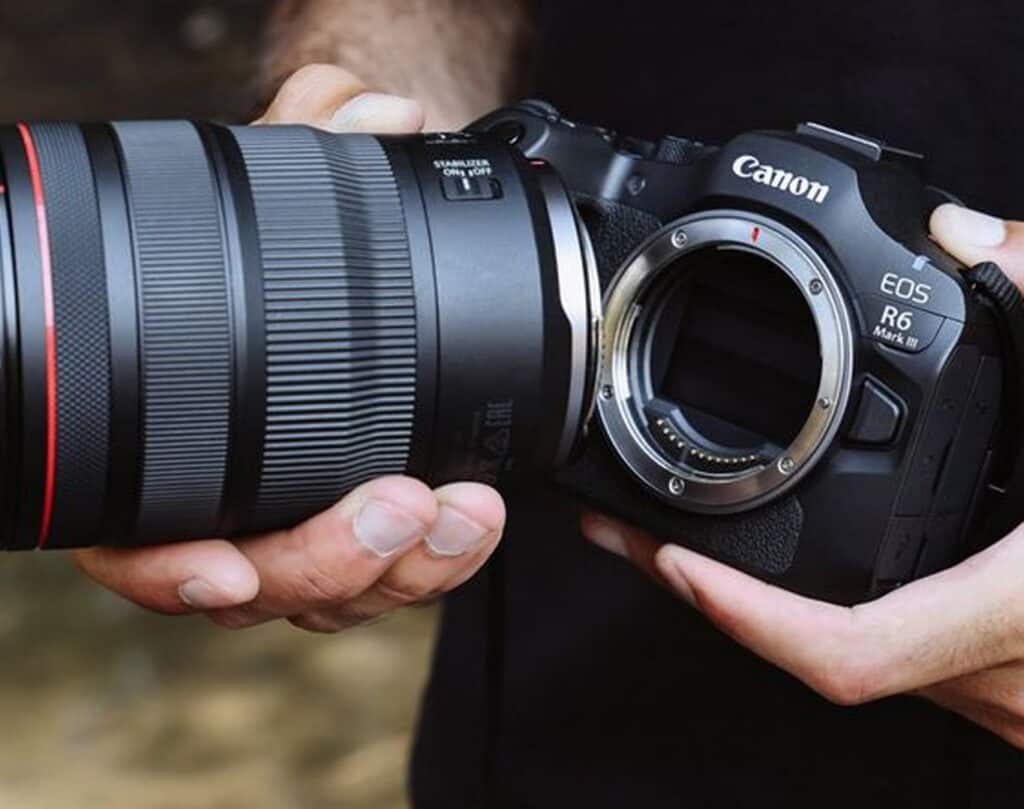 Close-up of a Canon EOS R6 Mark II camera body being held with a large zoom lens near the mount.