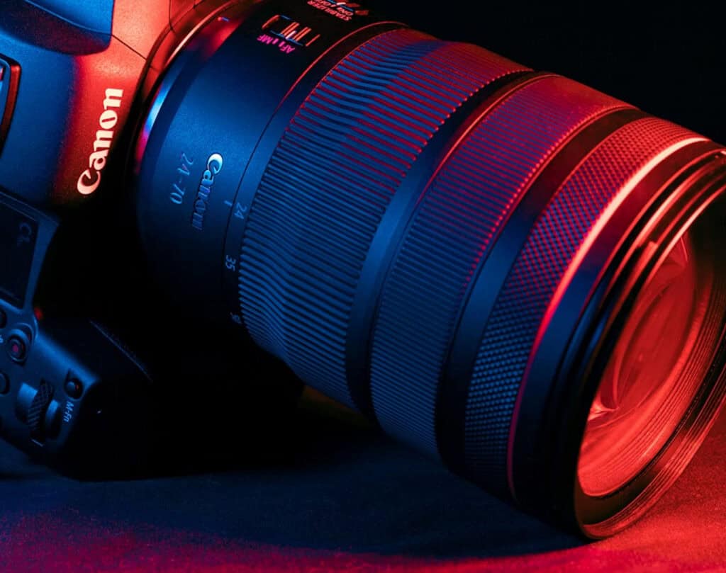 Close-up of a Canon camera with a large zoom lens under blue and red lightingeg.