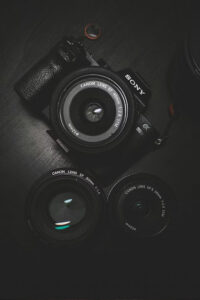 Sony camera body with three Canon lenses laid out on a dark surface, flat lay style mix of brands