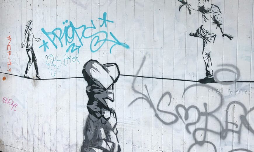 Street-4 | Photography and video news, reviews and tips | Henry's Camera Street-art mural of a man on the right holding flowers toward a woman walking away on the left, with a large rock-like figure in the foreground and blue graffiti tags in the background.