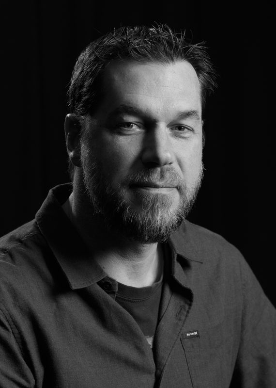 image004 | Photography and video news, reviews and tips | Henry's Camera Black-and-white portrait of a man with short dark hair and a trimmed beard, wearing a collared shirt, looking at the camera with a neutral expression.